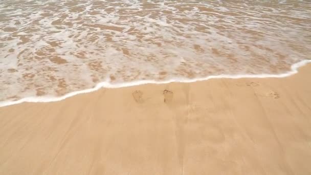 Homem salta longe da onda do oceano em uma praia arenosa — Vídeo de Stock