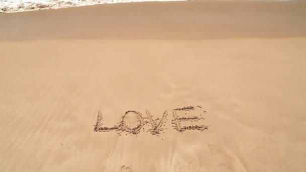 Ozeanwelle nähert sich Wort Liebe in Sand geschrieben — Stockvideo