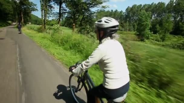 Женщина на велосипеде по дороге в сельской местности — стоковое видео