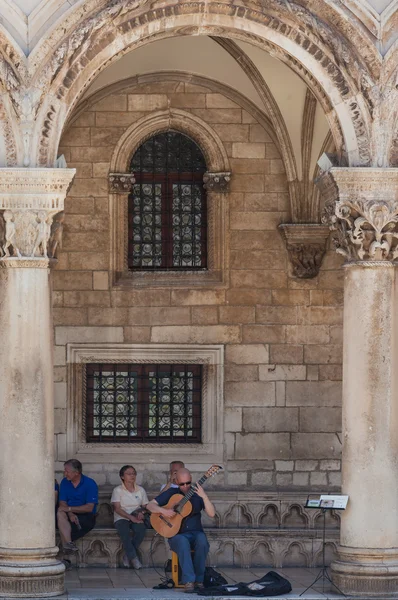 El hombre toca la guitarra frente al palacio del rector —  Fotos de Stock