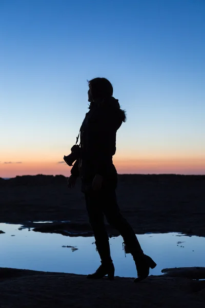 Silhouet van de vrouw op het strand bij zonsondergang. — Stockfoto