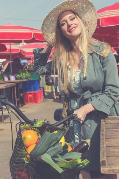 Attraente donna bionda con cappello di paglia e bici su Marketplace . — Foto Stock