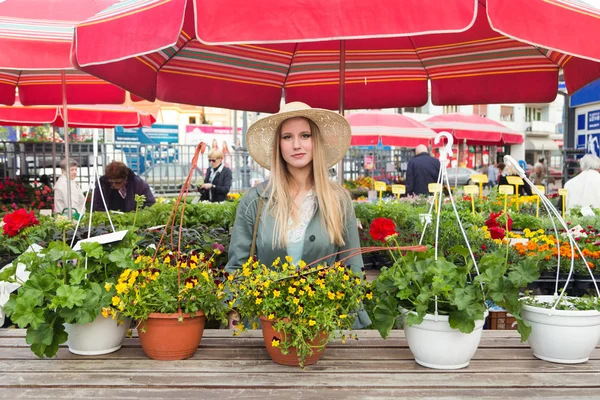 Attraente donna bionda con cappello di paglia in posa sul mercato dei fiori . — Foto Stock