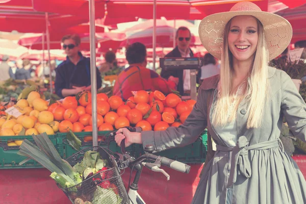 Attractive blonde woman with straw hat and bike on Marketplace. — Stock Photo, Image