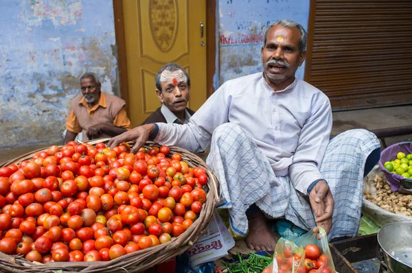 Kruidenier zet tomaten uit mandje — Stockfoto