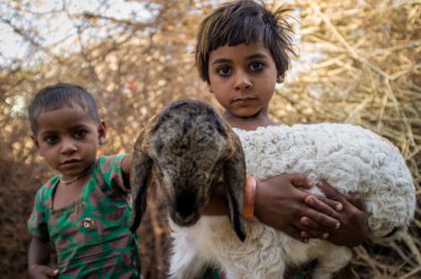 girls in stable with small lamb