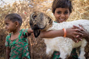 girls in stable with small lamb