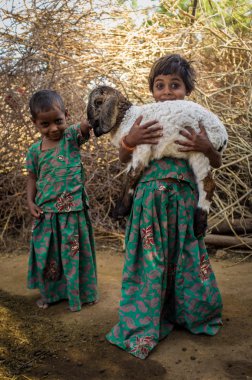 girls in stable with small lamb