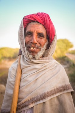 Elderly Rabari tribesman stands with axe