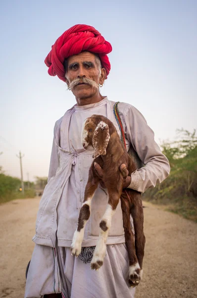 Elderly Rabari tribesman holds goatling — ストック写真