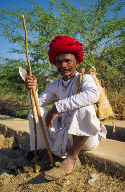 tribesman with red turban sits