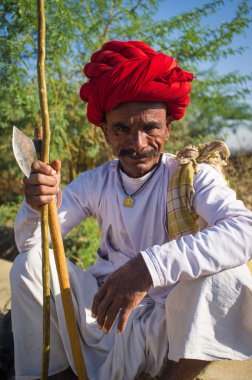 Rabari tribesman holds axe and stick