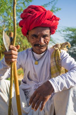 Rabari tribesman holds axe and stick