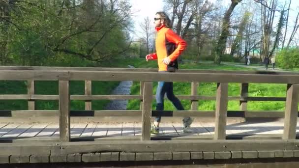 Runner przekraczania mostu w parku. — Wideo stockowe