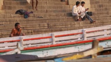 Varanasi, Ganj Nehri teknelerle önünde ghat, oturan adam.