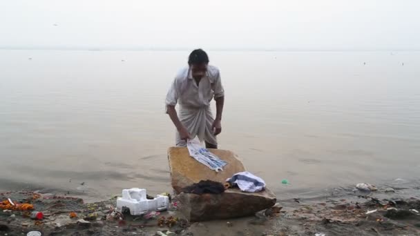 Hombre azotando ropa de piedra — Vídeos de Stock