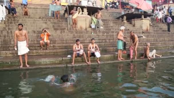 People bathing and sitting at ghat of Ganges river in Varanasi. — Stock Video