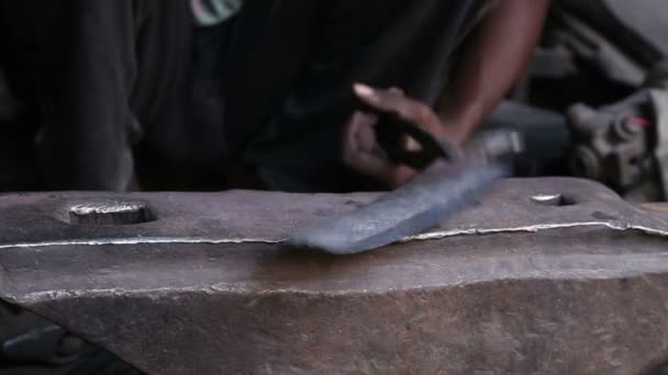 Homme aiguisant un outil 