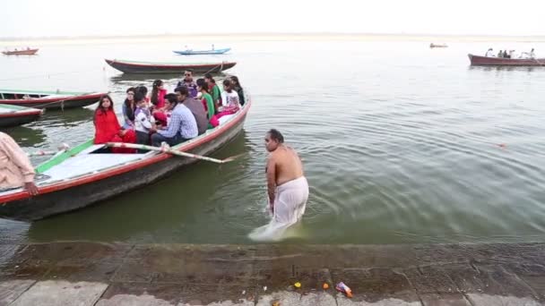 Boat arriving to the shore of Ganges, while man baths aside. — Stock Video
