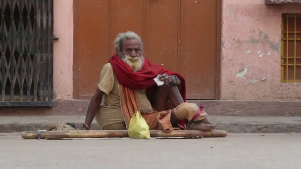 Portret van oude bedelaar op straat in Varanasi, met passerende mensen. — Stockvideo