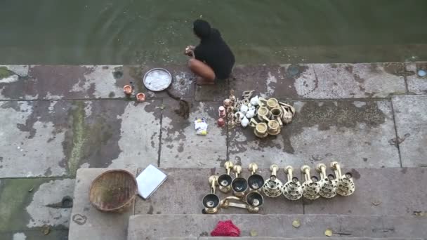 Vysoký úhel pohled na člověka mytí dekorativní stojany a pokrmy v Ganges. — Stock video