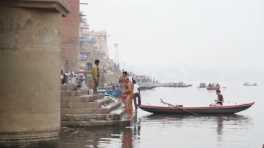 Erkek adam Nehri üzerinde tekne ile banyo sonra Ganj iskelede duran.