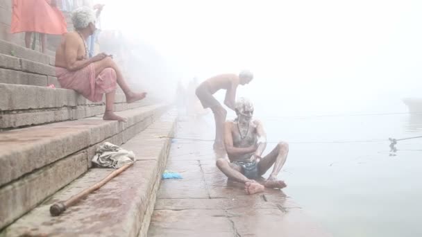 Homem esfregando seu corpo na costa do nevoeiro rio Ganges em Varanasi . — Vídeo de Stock