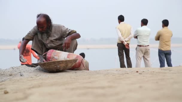 Hombre buscando a través de la arena en la orilla del Ganges — Vídeo de stock