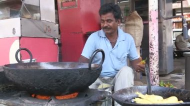 Samosa pişirme sırasında Hintli adam gülümsüyor.