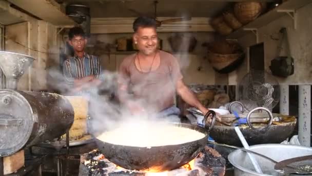 Man steka mat i en stor gryta. — Stockvideo