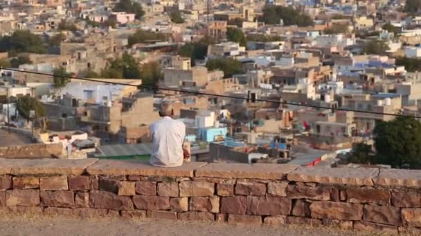 Hombre sentado en la pared viendo paisaje urbano — Vídeos de Stock