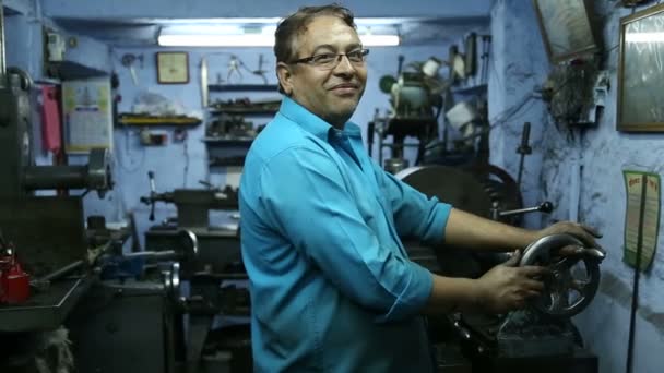 Porträt eines indischen Mannes, der in einer Werkstatt in Jodhpur an einer Maschine arbeitet. — Stockvideo