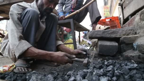 Seorang pria menghancurkan batu di tanah . — Stok Video