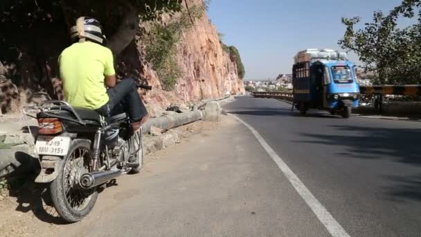 Hombre en moto de pie junto a la carretera — Vídeos de Stock