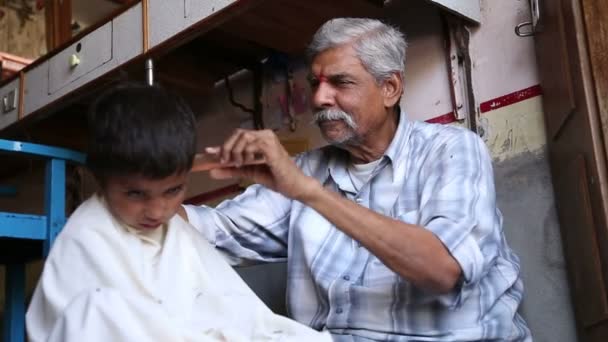 Indian man cutting boy's hair — Stock Video