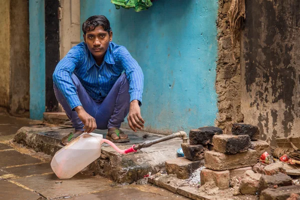 Homem indiano jovem enchendo garrafa de água — Fotografia de Stock