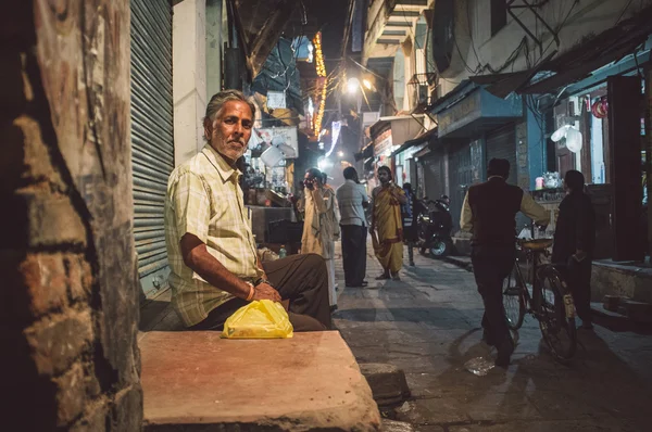 Indisk man sitter infront av stängd butik — Stockfoto