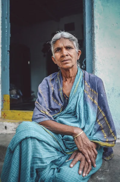 woman sits in sari in-front of home