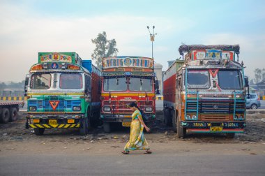 Woman walking by parked trucks