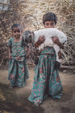 girls in stable with small lamb