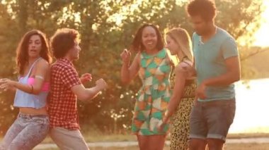 Beş arkadaş günbatımında dans