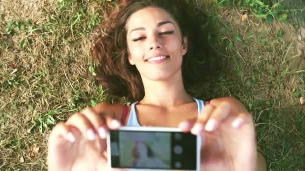 Drie jonge volwassenen nemen van een selfie liggend op het gras — Stockvideo