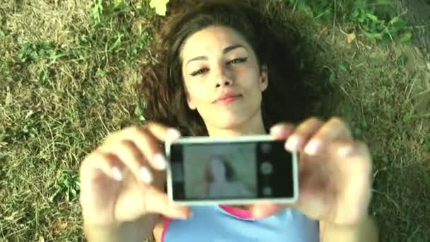 Tři mladí dospělí s selfie, ležící na trávě — Stock video