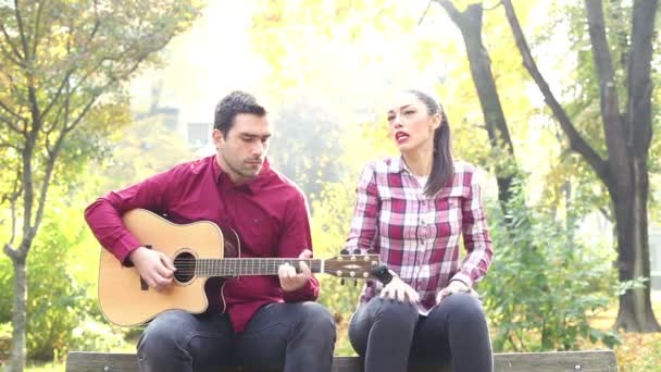 Мужчина играет на гитаре, а женщина поет — стоковое видео