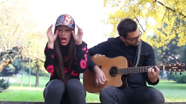 男がギターを弾きながら歌っている女性 — ストック動画