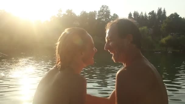 Ζευγάρι συνεδρίαση επόμενη ποταμού στο ηλιοβασίλεμα — Αρχείο Βίντεο
