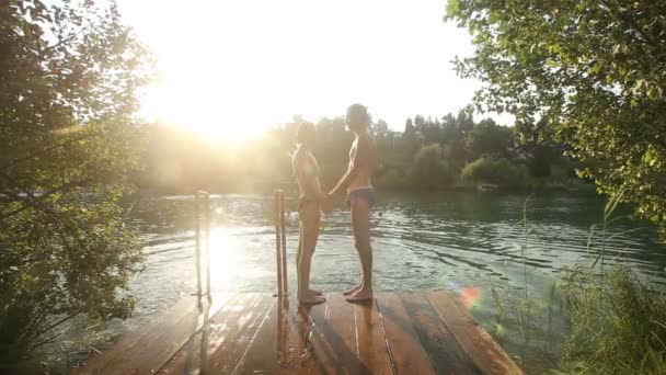 Pareja sentada al lado del río al atardecer — Vídeo de stock