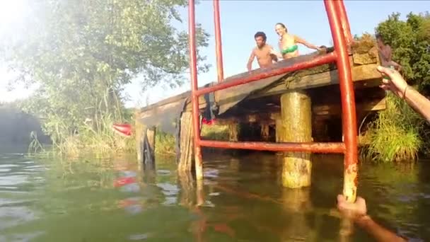 Друзі бігають і стрибають у річку — стокове відео