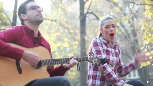 Мужчина играет на гитаре, а женщина поет — стоковое видео