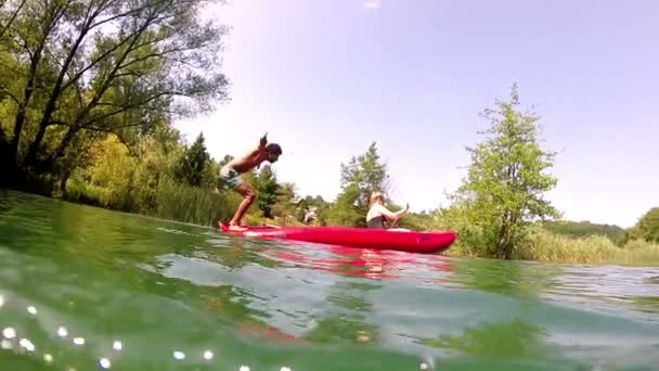 Человек, прыгающий с каноэ в воду — стоковое видео